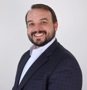 A man in a suit and tie smiling for the camera.